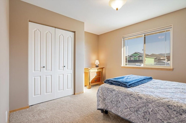 carpeted bedroom with a closet and baseboards