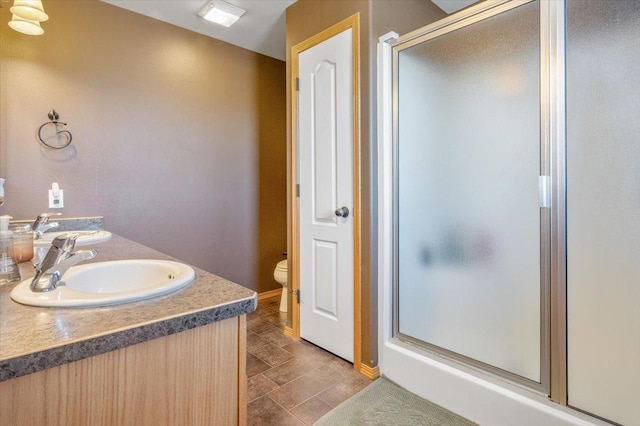 full bathroom featuring double vanity, a stall shower, toilet, and a sink