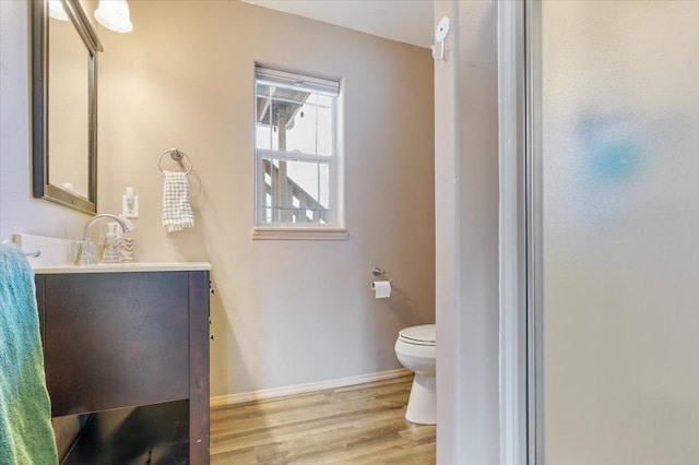 bathroom with baseboards, toilet, wood finished floors, and vanity