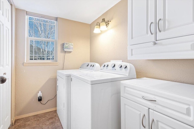 washroom with cabinet space, baseboards, a textured wall, and washer and clothes dryer