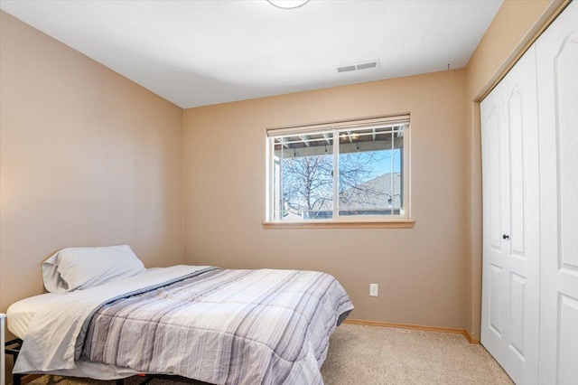 carpeted bedroom featuring baseboards, visible vents, and a closet