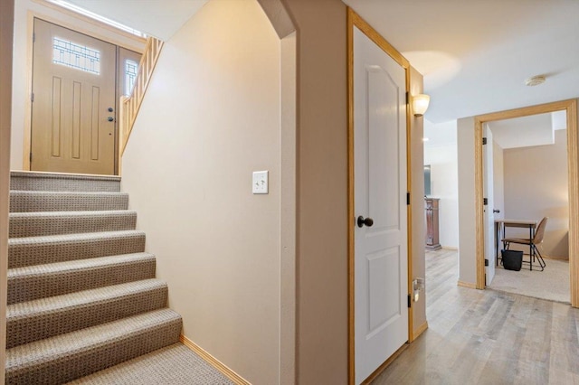 stairway with baseboards, arched walkways, and wood finished floors