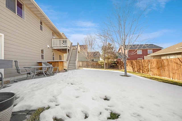 snow covered patio with stairs and a fenced backyard