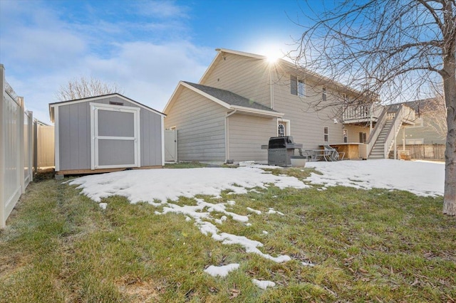 snow covered property featuring stairs, an outdoor structure, a storage unit, and a fenced backyard