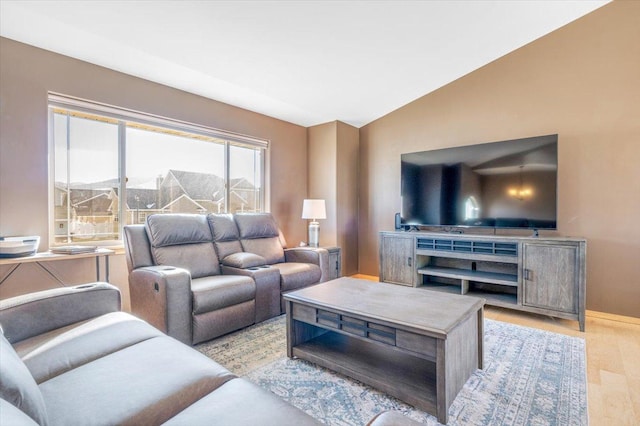 living area featuring lofted ceiling, light wood-style floors, and baseboards