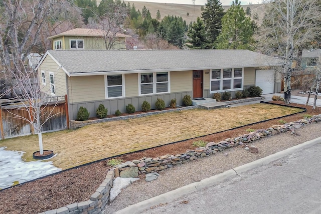 view of front facade with a garage, driveway, board and batten siding, and a front lawn