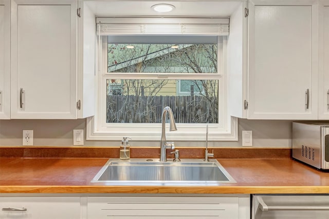 kitchen with dark countertops, white cabinets, appliances with stainless steel finishes, and a sink