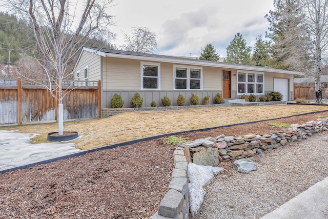 ranch-style home with board and batten siding, a garage, and fence