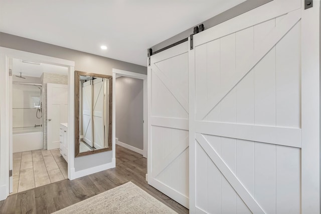 hall with recessed lighting, a barn door, baseboards, and wood finished floors