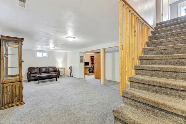 living area featuring visible vents, carpet, and stairs