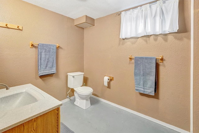 bathroom with vanity, baseboards, concrete floors, toilet, and a textured wall