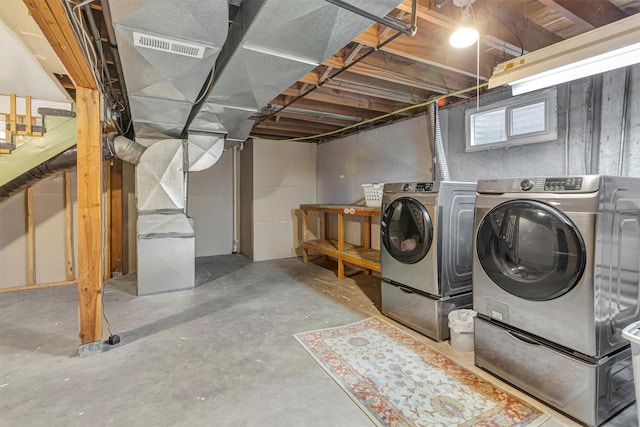 below grade area featuring washing machine and clothes dryer, visible vents, and heating unit