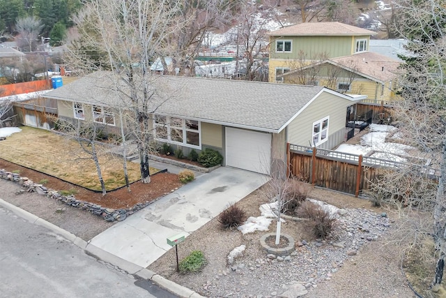 single story home featuring driveway, an attached garage, roof with shingles, and fence