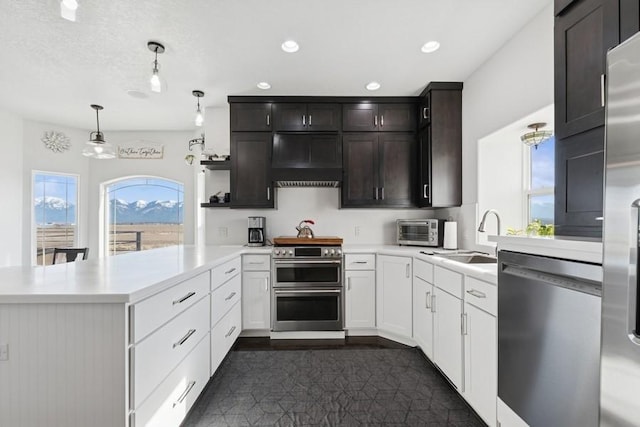 kitchen with a sink, light countertops, a peninsula, stainless steel appliances, and open shelves