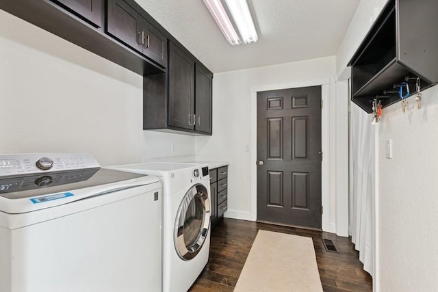 laundry area with dark wood-style floors, visible vents, washing machine and dryer, and cabinet space