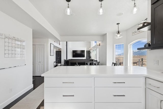 kitchen featuring open floor plan, light countertops, a peninsula, hanging light fixtures, and white cabinets