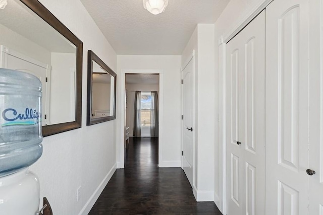 corridor with baseboards, a textured ceiling, and dark wood finished floors