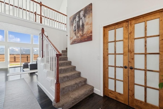 stairs with french doors, a high ceiling, and hardwood / wood-style flooring