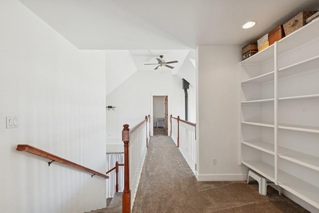 hall featuring baseboards, an upstairs landing, lofted ceiling, and carpet flooring