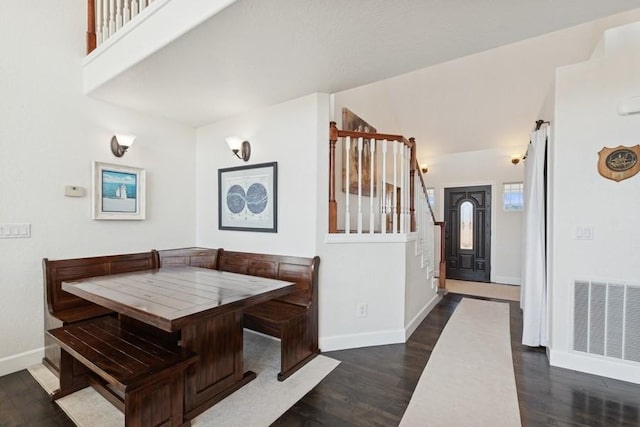 dining space with visible vents, dark wood finished floors, breakfast area, baseboards, and stairs