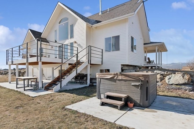 back of property featuring stairway, a patio, and a hot tub