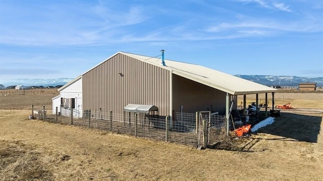 view of outbuilding featuring an outdoor structure, a rural view, a mountain view, and an exterior structure