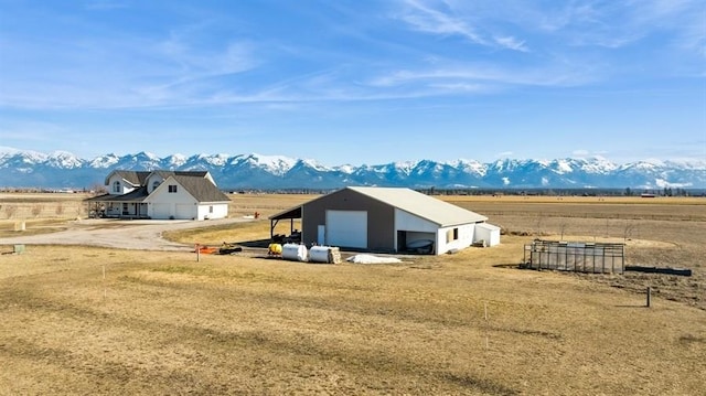 view of yard featuring an outbuilding, a rural view, a mountain view, and a detached garage