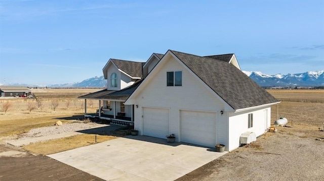 view of side of property with covered porch, a mountain view, and concrete driveway