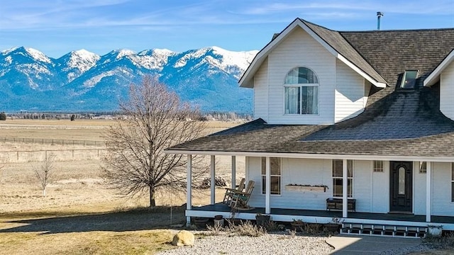 exterior space with a mountain view, roof with shingles, and a porch