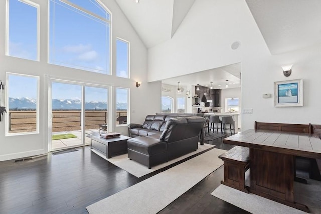 living room featuring a healthy amount of sunlight, a mountain view, dark wood-type flooring, and lofted ceiling