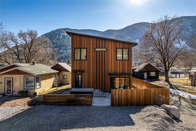 contemporary house featuring a fenced front yard, a mountain view, and board and batten siding