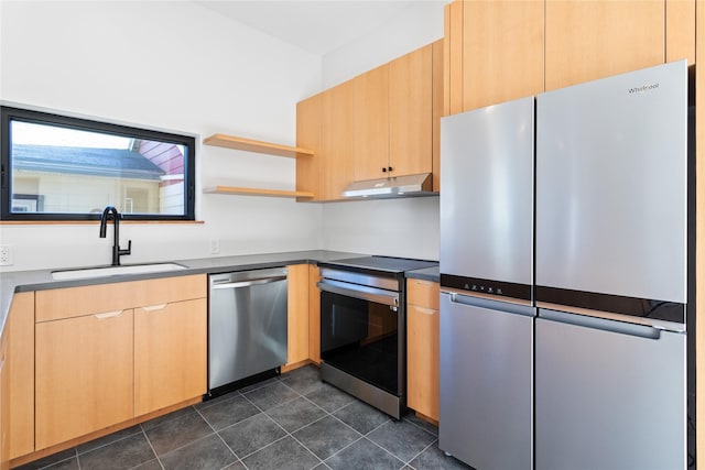 kitchen featuring dark countertops, under cabinet range hood, light brown cabinetry, appliances with stainless steel finishes, and a sink