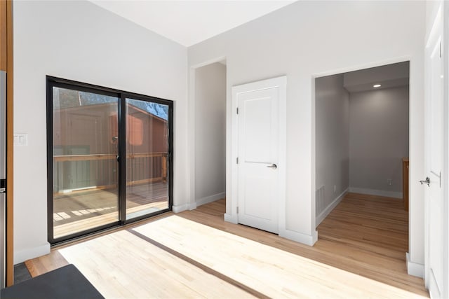 interior space with access to exterior, visible vents, light wood finished floors, and baseboards