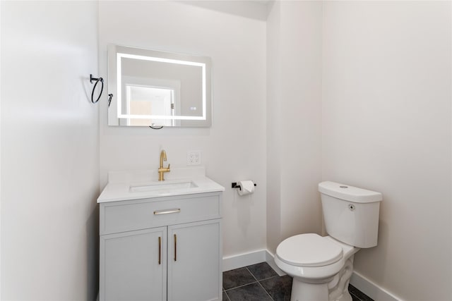 bathroom featuring baseboards, toilet, vanity, and tile patterned flooring