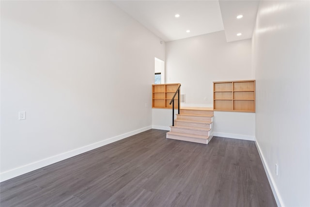 empty room featuring recessed lighting, baseboards, and dark wood-type flooring