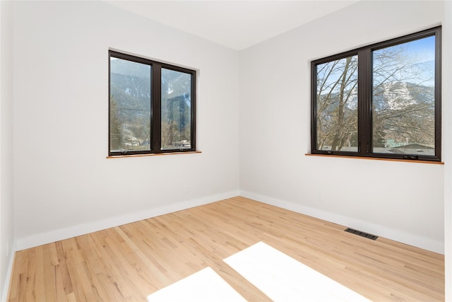 unfurnished room with visible vents, baseboards, and wood finished floors