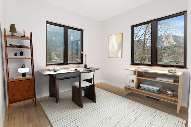 home office with visible vents, baseboards, and wood finished floors