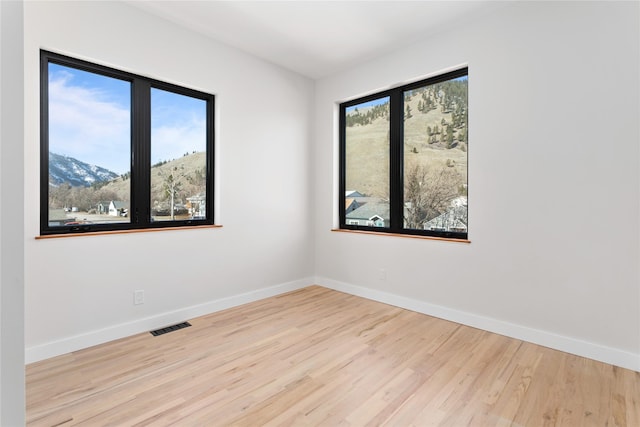 spare room with visible vents, baseboards, wood finished floors, and a mountain view