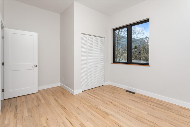 unfurnished bedroom with a closet, visible vents, baseboards, and light wood-style floors