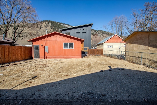 rear view of house with a mountain view and a fenced backyard