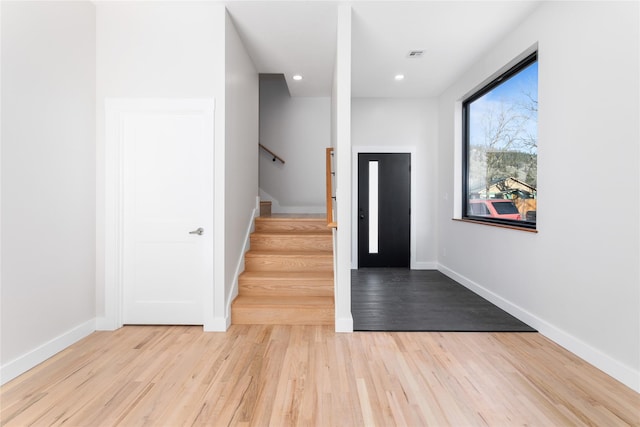 foyer featuring stairs, baseboards, and light wood finished floors