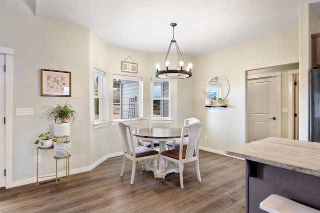 dining area featuring visible vents, a notable chandelier, wood finished floors, and baseboards