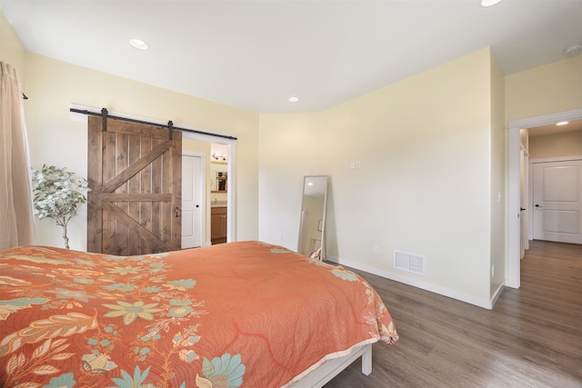 bedroom with wood finished floors, visible vents, baseboards, recessed lighting, and a barn door