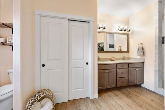 full bathroom with double vanity, toilet, wood finished floors, and a sink