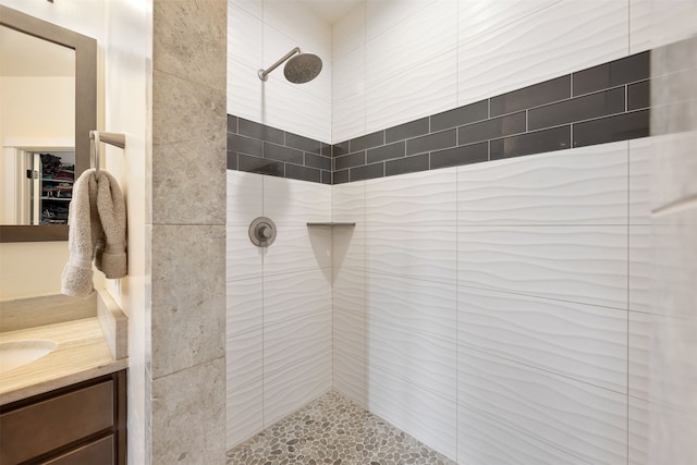 bathroom featuring tiled shower and vanity