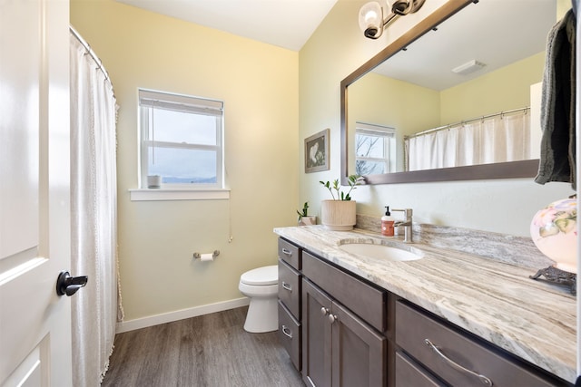 bathroom with visible vents, baseboards, toilet, wood finished floors, and vanity