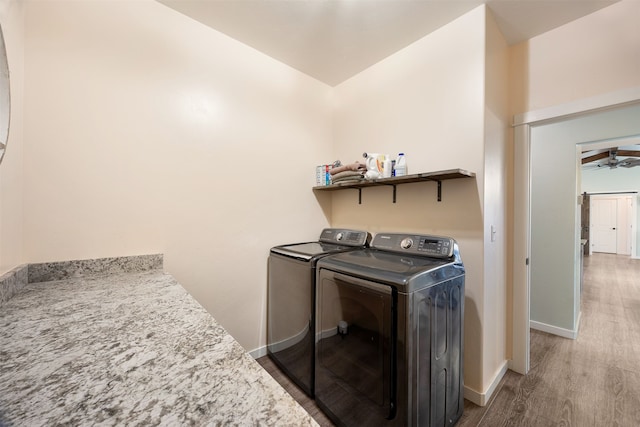 laundry room with baseboards, wood finished floors, laundry area, and washing machine and clothes dryer