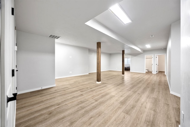 basement with light wood-style floors, visible vents, and baseboards