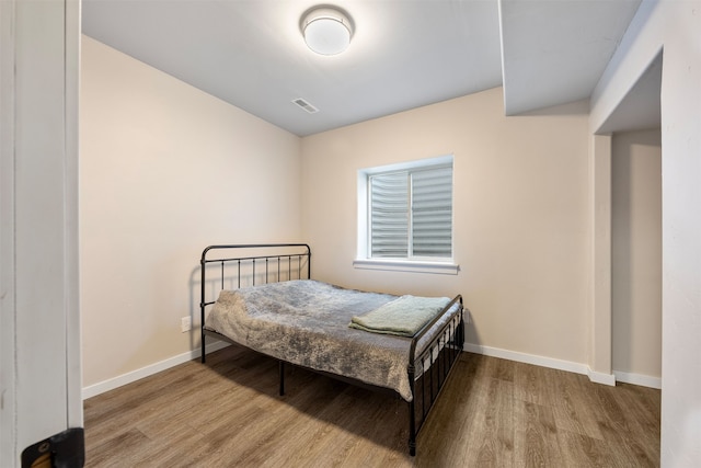 bedroom with visible vents, baseboards, and wood finished floors