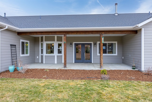 property entrance featuring a patio area, a lawn, french doors, and a shingled roof